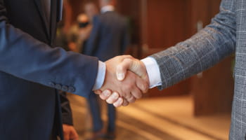 Two people in suits shake hands.