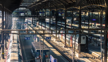 Trains at platforms beneath the large roof of a railway station.