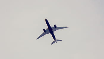 A passenger aircraft seen from below against a pale sky.
